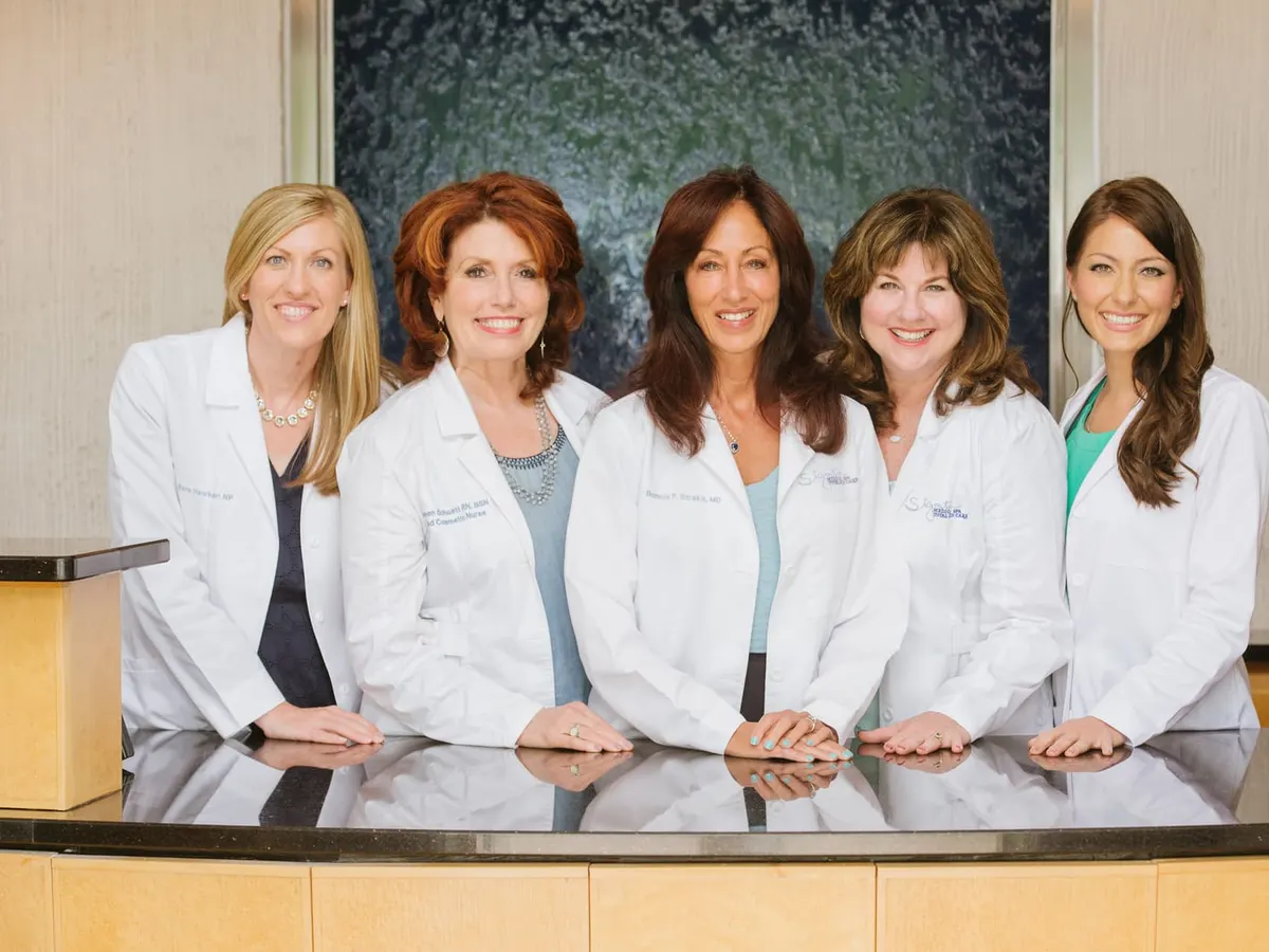 Five members of the clinical team in white coats, standing together behind a long reception counter