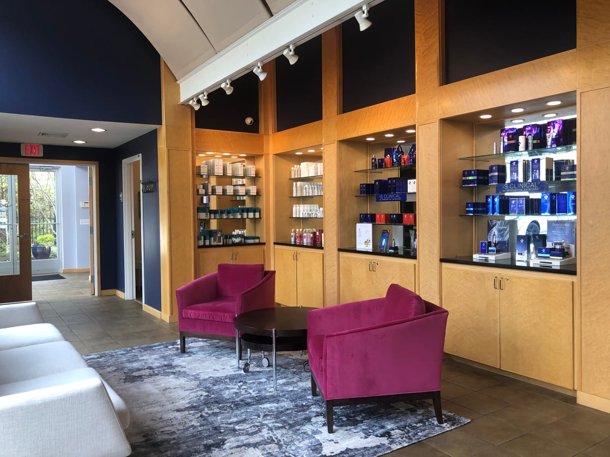 The Signature Medical Spa lobby: two magenta armchairs beside lit wooden shelves of skin care products